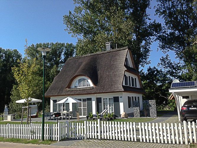 Außenansicht von Ferienhaus Albatros mit großer Südterrasse, stationärem Grill, Strandkorb und Carport